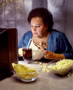 heavy woman watching TV while eating junk food