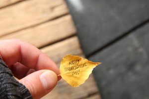 hand holding autumn leaf with an inscription Happy Thanksgiving day